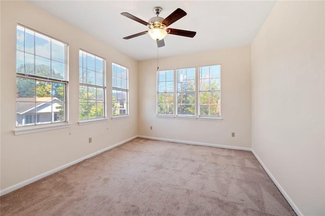 carpeted spare room featuring baseboards and ceiling fan