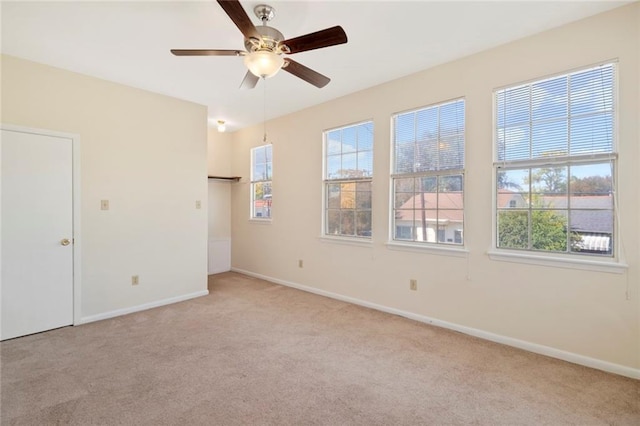 unfurnished room with light carpet, healthy amount of natural light, and a ceiling fan