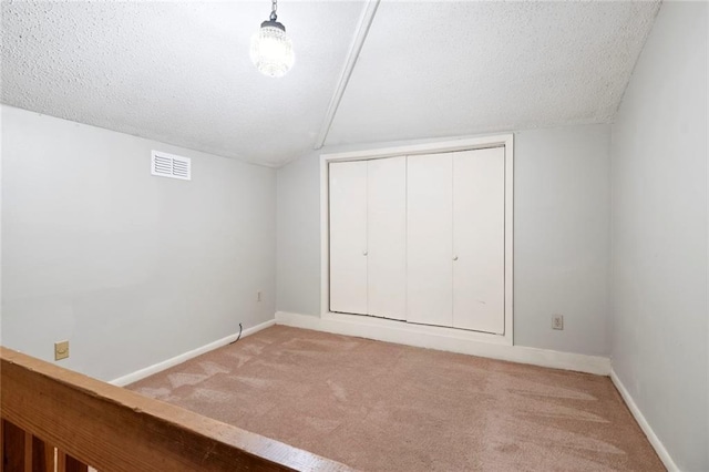 unfurnished bedroom with carpet floors, vaulted ceiling, baseboards, a closet, and a textured ceiling