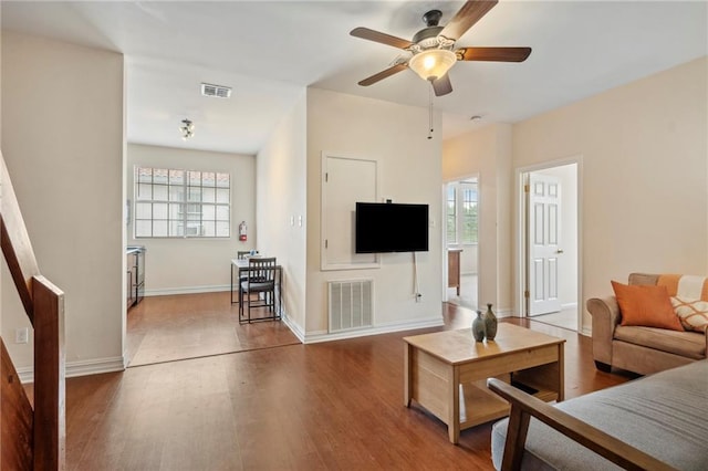 living area with plenty of natural light, wood finished floors, and ceiling fan