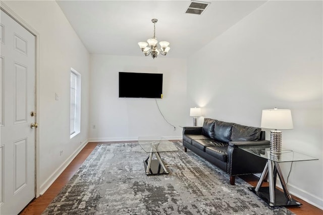 living area with a chandelier, baseboards, and wood finished floors