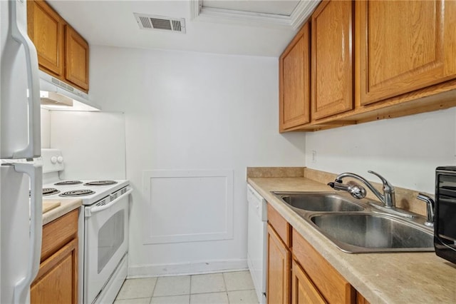 kitchen with a sink, white appliances, under cabinet range hood, light tile patterned flooring, and light countertops