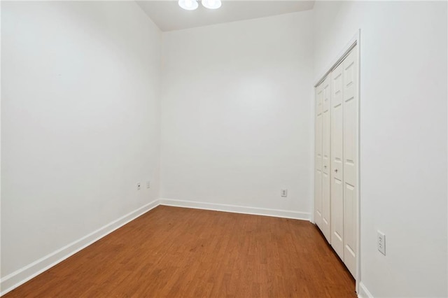 unfurnished bedroom featuring wood finished floors, a closet, and baseboards