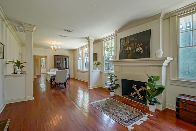 living area featuring a chandelier, visible vents, decorative columns, and ornamental molding
