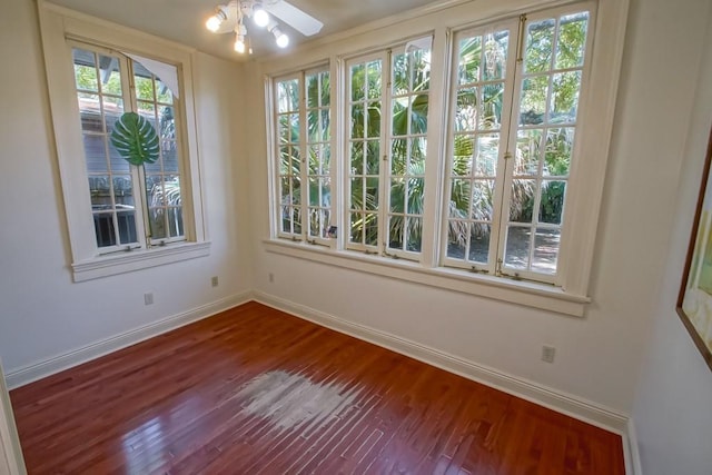spare room featuring baseboards, ceiling fan, and dark wood-style floors