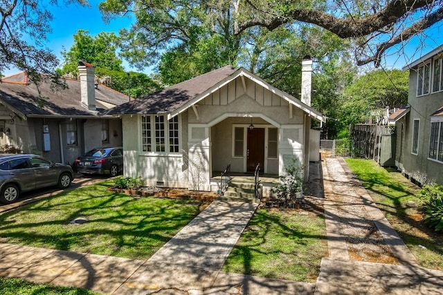 bungalow-style home with crawl space, fence, a chimney, and a front yard