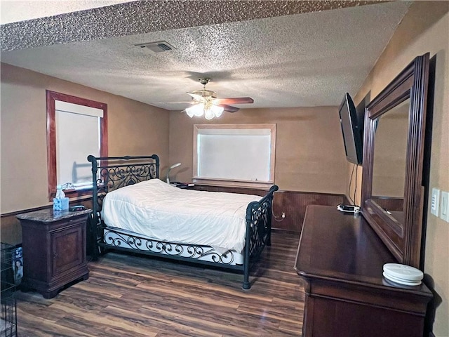 bedroom featuring a textured ceiling, visible vents, dark wood-style flooring, and a ceiling fan