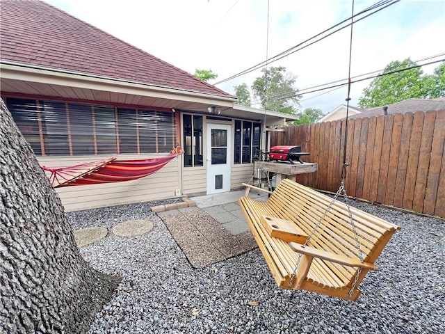 view of patio featuring a grill, a sunroom, and fence