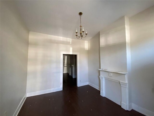 122628 Carondelet St, New Orleans, LA 70130 - unfurnished living room with a chandelier, baseboards, and wood finished floors