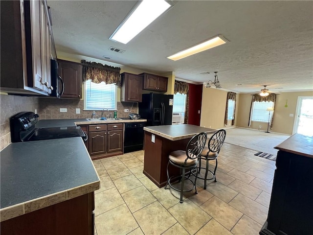 119 Carr Dr, Slidell, LA 70458 - kitchen with a center island, a breakfast bar, a sink, open floor plan, and black appliances