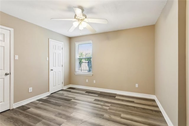 empty room featuring ceiling fan, baseboards, and wood finished floors