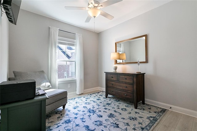 sitting room with light wood-type flooring, a ceiling fan, and baseboards