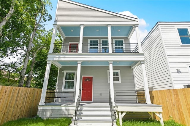 view of front of house featuring a porch, fence, and a balcony