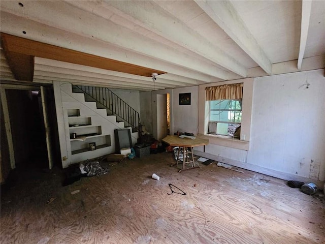 unfurnished living room featuring stairway and beamed ceiling