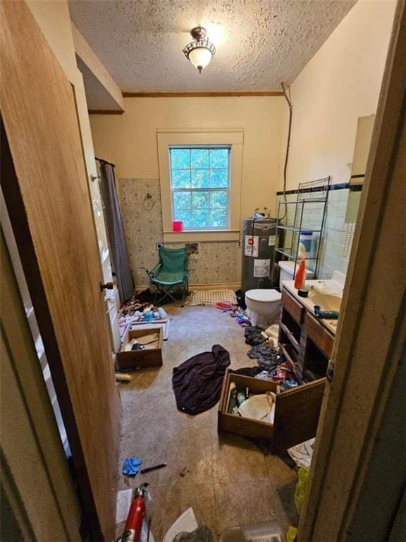 bathroom with water heater, a textured ceiling, toilet, and vanity