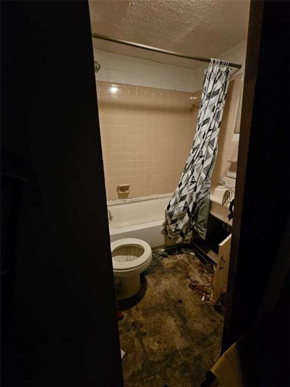 full bathroom featuring toilet, a textured ceiling, and shower / bath combo