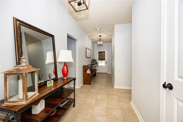 hall with light tile patterned floors, visible vents, and baseboards