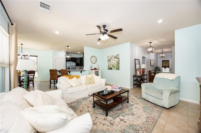 living room featuring recessed lighting, baseboards, visible vents, light tile patterned flooring, and ceiling fan with notable chandelier