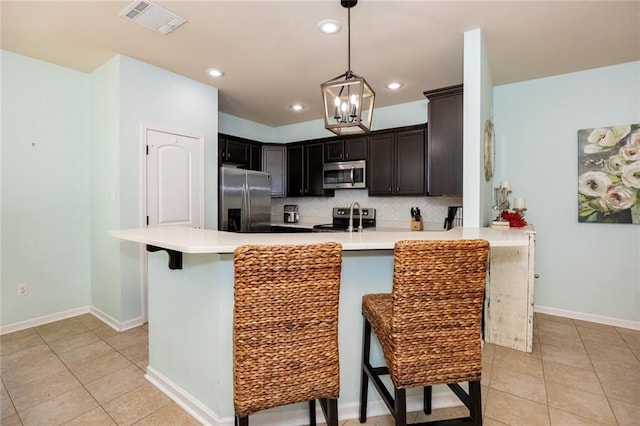 kitchen featuring a peninsula, light tile patterned floors, a kitchen bar, stainless steel appliances, and visible vents