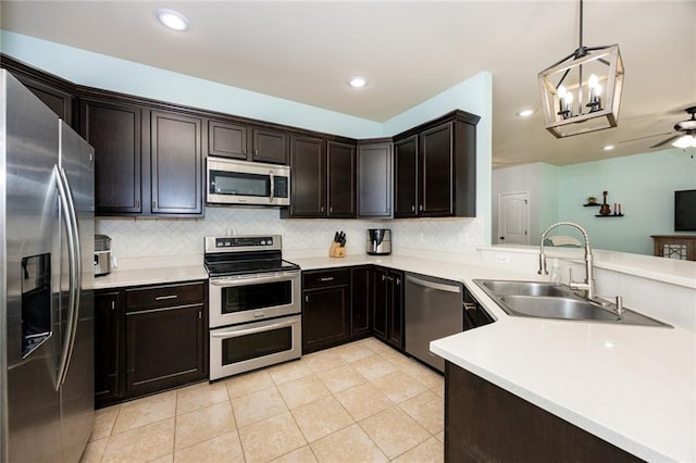 kitchen with a sink, stainless steel appliances, light countertops, decorative backsplash, and light tile patterned flooring
