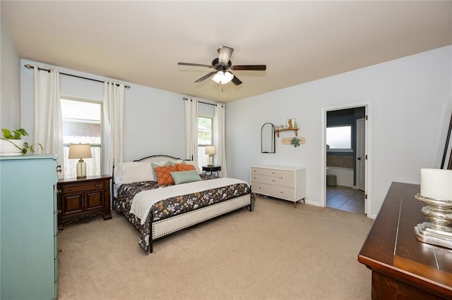 bedroom with ensuite bath, light carpet, and ceiling fan