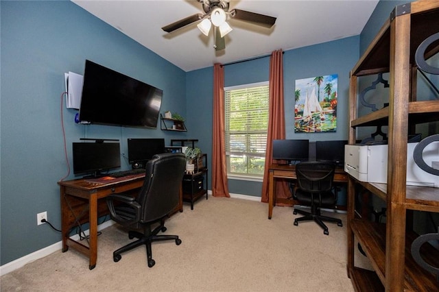 carpeted office space featuring baseboards and a ceiling fan
