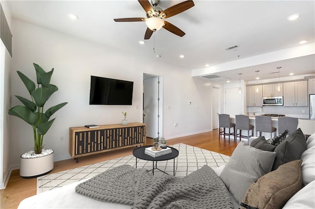 living room with light wood finished floors, recessed lighting, ceiling fan, and baseboards