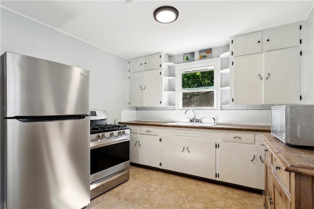 1615 Trechel Dr, Covington, LA 70433 - kitchen with light tile patterned flooring, a sink, white cabinetry, open shelves, and stainless steel appliances