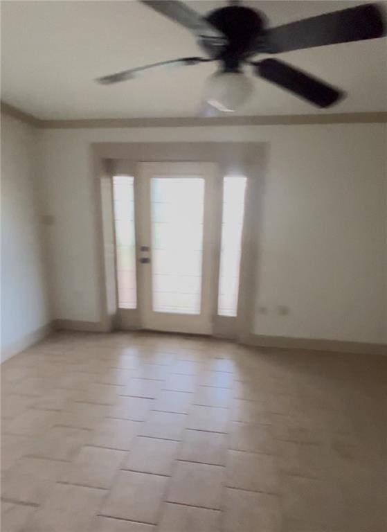 unfurnished room featuring a ceiling fan, ornamental molding, a healthy amount of sunlight, and baseboards