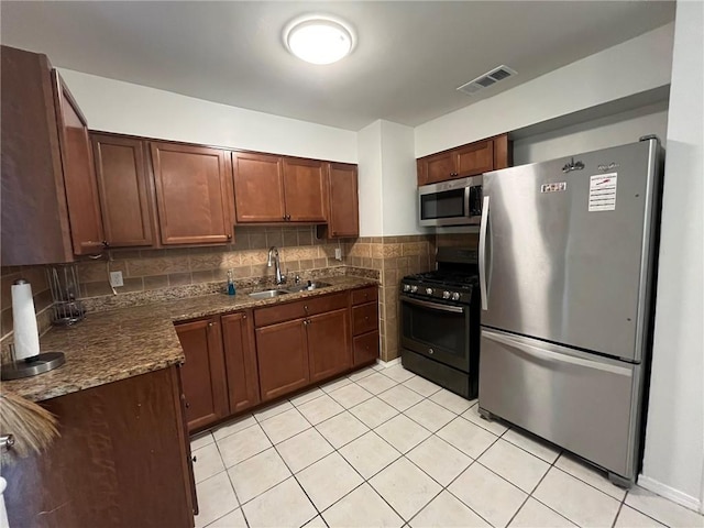 1053 Sandalwood Dr, Harvey, LA 70058 - kitchen with a sink, stainless steel appliances, dark stone countertops, light tile patterned flooring, and visible vents