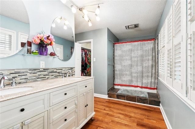 47 Yellowstone Dr, New Orleans, LA 70131 - full bathroom with double vanity, backsplash, wood finished floors, a textured ceiling, and baseboards