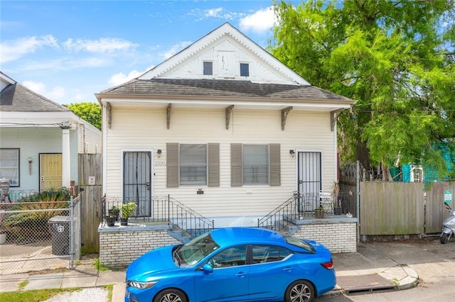 shotgun-style home with roof with shingles and fence