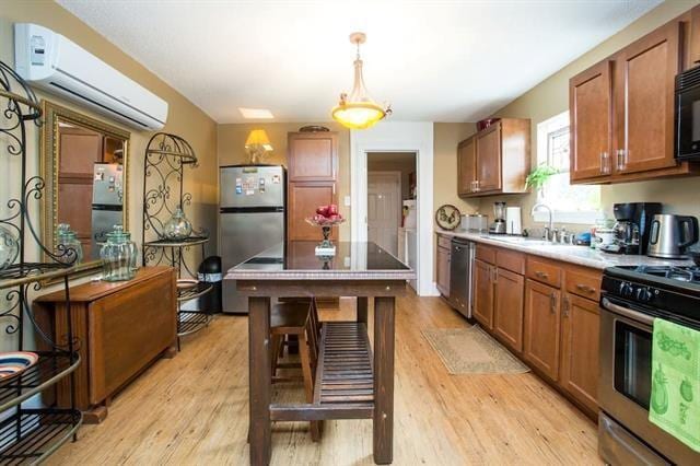 kitchen featuring a wall mounted AC, light wood finished floors, a sink, brown cabinets, and stainless steel appliances