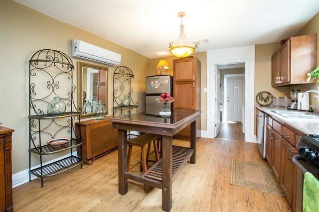 kitchen featuring a sink, a wall mounted air conditioner, light wood finished floors, light countertops, and appliances with stainless steel finishes
