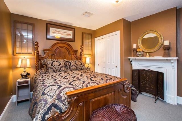 carpeted bedroom featuring a fireplace, a closet, baseboards, and visible vents