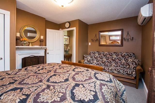 bedroom with a wall mounted air conditioner, a textured ceiling, and carpet floors