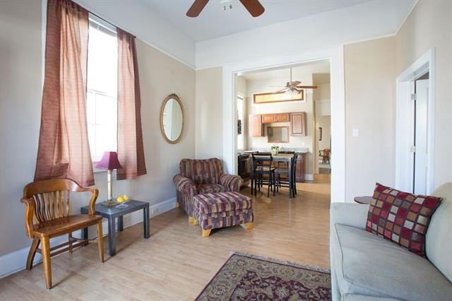 living area with ceiling fan, light wood-style flooring, and baseboards