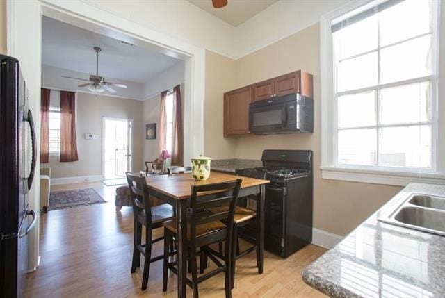 kitchen with a healthy amount of sunlight, baseboards, black appliances, and a ceiling fan