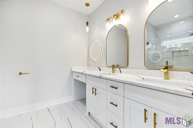 full bath with double vanity, a shower, baseboards, and a sink