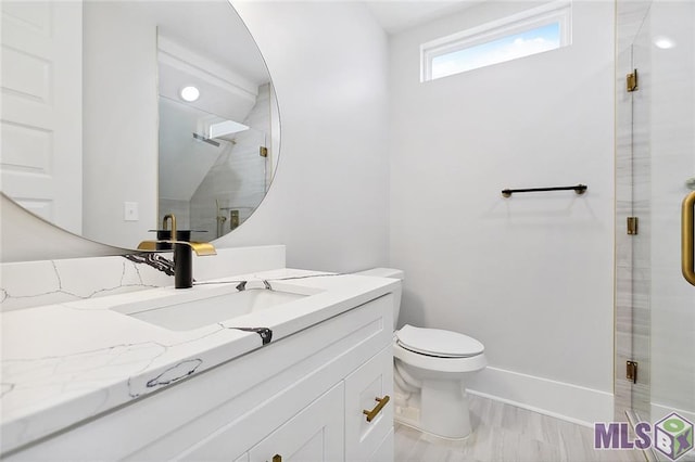 bathroom featuring a stall shower, baseboards, vanity, and toilet