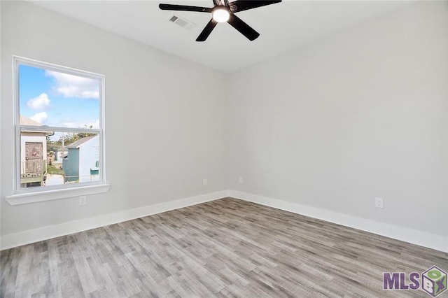 empty room featuring baseboards, visible vents, wood finished floors, and a ceiling fan