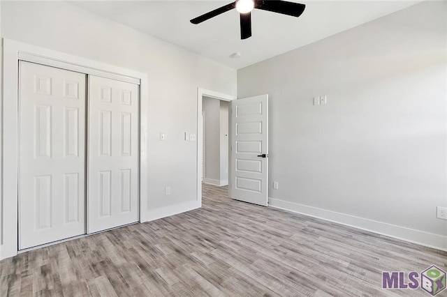 unfurnished bedroom featuring ceiling fan, a closet, baseboards, and wood finished floors