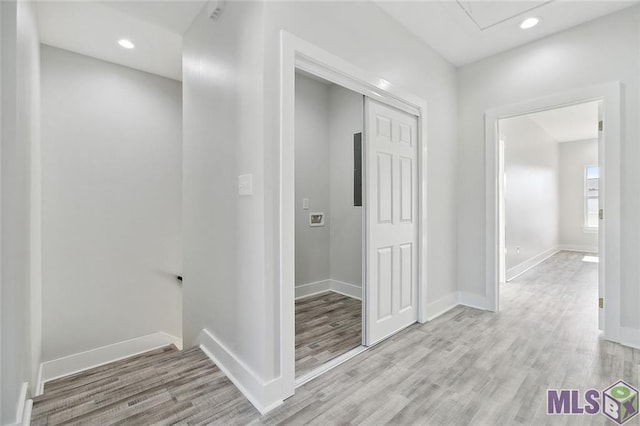 corridor with light wood-style flooring, attic access, baseboards, and recessed lighting