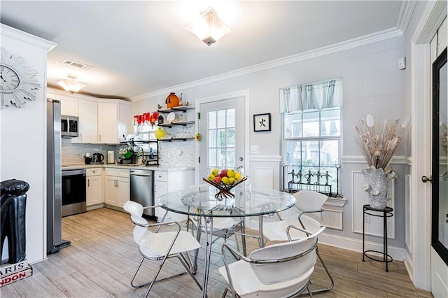dining space featuring crown molding and light wood-style flooring