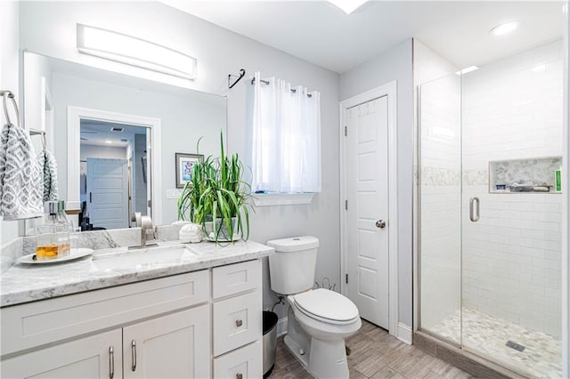 full bath featuring a stall shower, wood finished floors, vanity, and toilet