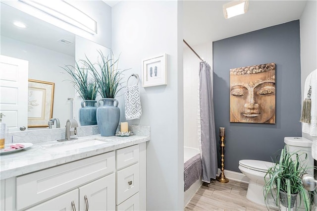 bathroom featuring toilet, vanity, wood finished floors, shower / bath combination with curtain, and baseboards