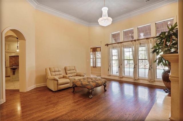 717 Tunica Bnd, Covington, LA 70433 - sitting room with arched walkways, wood finished floors, crown molding, baseboards, and a chandelier