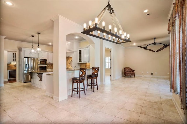 717 Tunica Bnd, Covington, LA 70433 - kitchen featuring appliances with stainless steel finishes, ornamental molding, a kitchen breakfast bar, open floor plan, and arched walkways