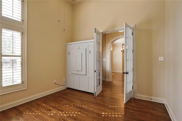 717 Tunica Bnd, Covington, LA 70433 - unfurnished bedroom with arched walkways, dark wood-type flooring, and baseboards