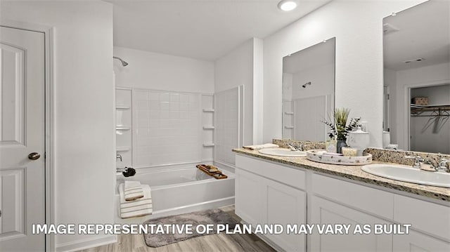 bathroom with wood finished floors, double vanity, and shower / washtub combination